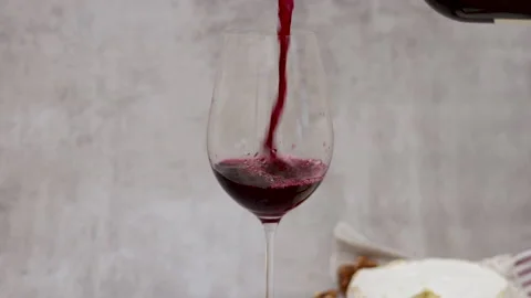 Red wine pour flows from bottle in glass gray tiles background Stock Footage 239303147
