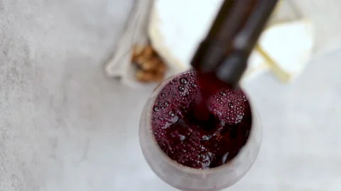 Red wine pour flows from bottle in glass gray tiles background Stock Footage 239303194