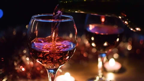 Red wine is poured into glasses. Light garlands in the background. Stock-Footage 97367388
