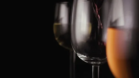 Red wine is poured into one of the three glasses Stock Footage 74877706