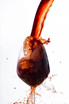 Red wine poured vigorously into a wine glass Stock Photos