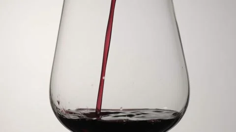Red wine is poured into a wine glass. White background Stock Footage