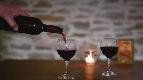 Red wine pours into glass on romantic candlelit table occasion slow motion Stock Footage 174795341