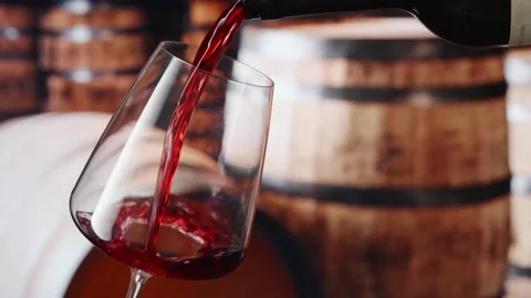 Red wine pours from the neck of the bottle into a wineglass Stock-Footage 148154449