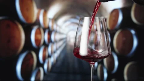 Red wine pours from the neck of the bottle into a wineglass Stock-Footage 148154484