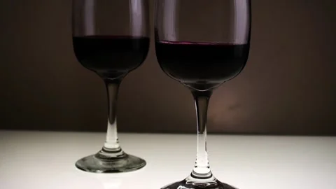 Red wine, in two glasses on a table against a dark background. Slow motion. Stock Footage 146640842