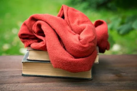 Red woman's scarf and a stack of books on a rustic table Stock Photos