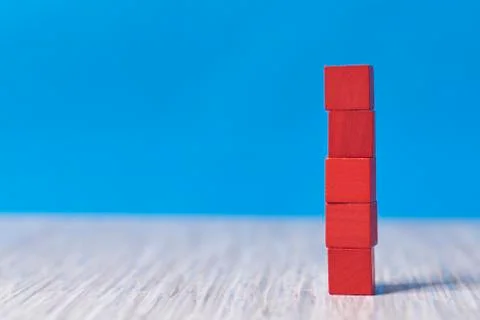 Red wood bricks tower. construction from wooden cubes. on a blue background Stock Photos