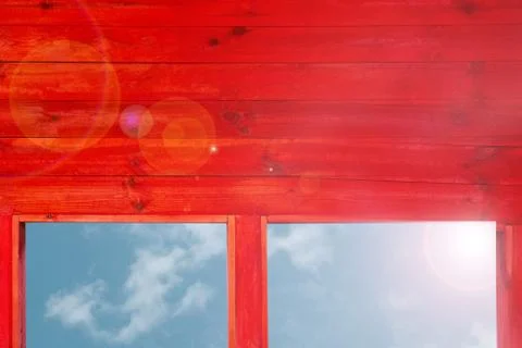 Red wood wall with windows to see blue sky and risen sun. Back light flash wi Stock-Fotos