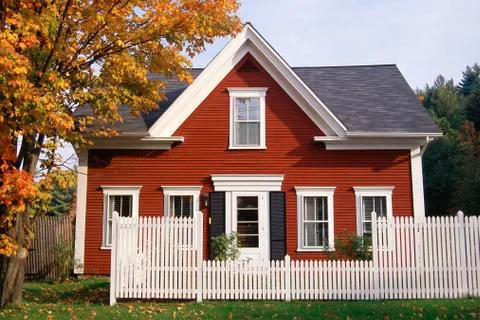 Red wooden house with white picket fence in autumn, New England Stock Photos