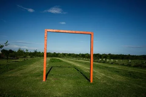 Red wooden rectangular frame on grassy field under clear blue sky Stock Photos