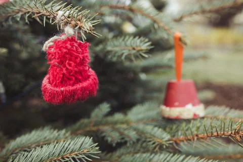 Red wool handmade small hat on Christmas tree outdoor. Diy decoration, yarn Foto stock