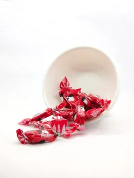 Red wrapper toffee in white bowl Stock Photos