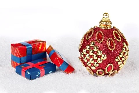 Red x-mas ball on snow with presents isolated white 库存照片