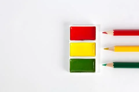 Red Yellow and Green solid watercolor pans and sharp colored pencils on white Stock Photos