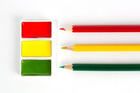 Red Yellow and Green solid watercolor pans and sharp colored pencils on white Stock Photos
