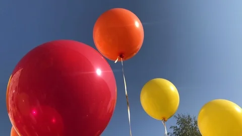 A red yellow balloon tied to a string floats in blue sky. Many colorful balloons Stock Footage