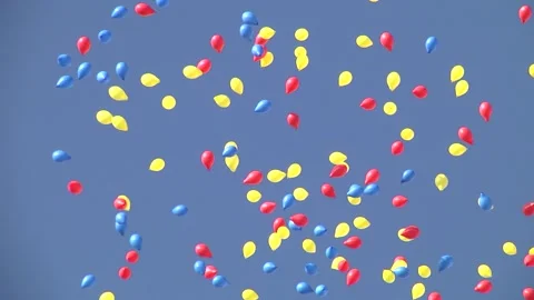 Red-yellow-blue colored balloons dancing in the clear blue sky during a demo Stock Footage 145489589