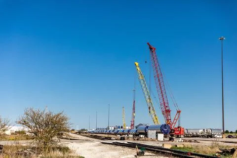 Red &amp; Yellow Cranes Loading Wind Turbine Shafts onto Railcars Stock Photos
