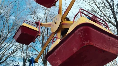 Red-yellow lonely empty deserted swing in an old abandoned amusement park Stock Footage 151924405