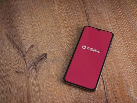 Redbubble app launch screen on smartphone on wooden background Stock Photos