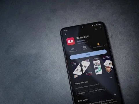 Redbubble app play store page on smartphone on a dark marble stone background Stock Photos