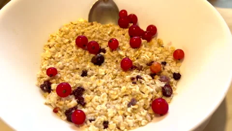 Redcurrants falling into oatmeal with spoon Stock Footage 311305428