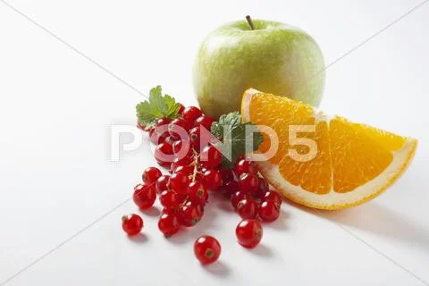 Redcurrants, an orange wedge and an apple Stock Photos