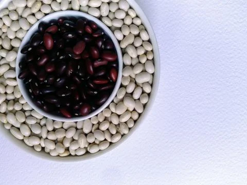 The reddish brown beans in a small white Cup are framed by white beans in a l Stock Photos