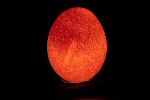 A reddish easter egg like picture of a raw egg through mobile flash light. Stock Photos