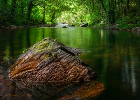Reddish rock in the middle of a river Stock Photos