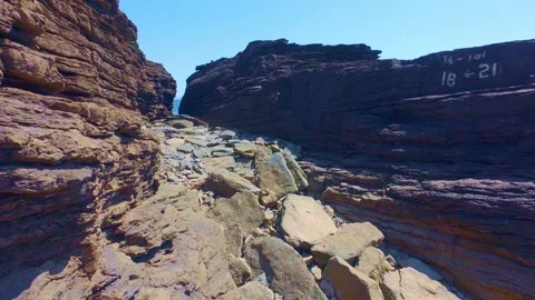 Reddish rocky cliff walls forming narrow coastal passage Stock Footage 340451365