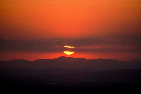 The reddish sun behind the mountains Stock Photos