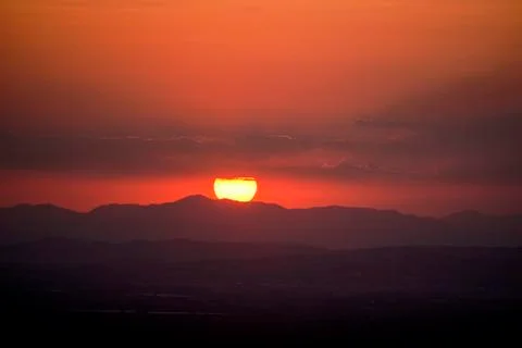 The reddish sun behind the mountains Stock Photos