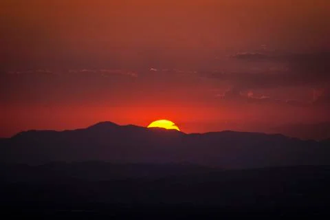 The reddish sun behind the mountains Stock Photos