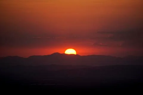 The reddish sun behind the mountains Stock Photos