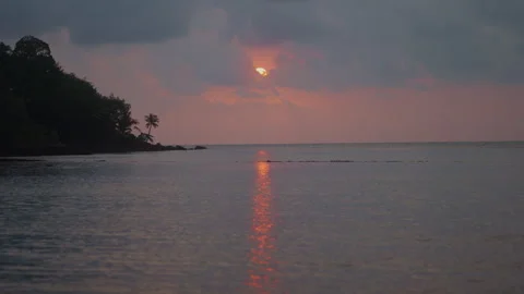 Reddish Sunset with Sun Setting Down Behind Clouds Over Sea Stock Footage 337533671