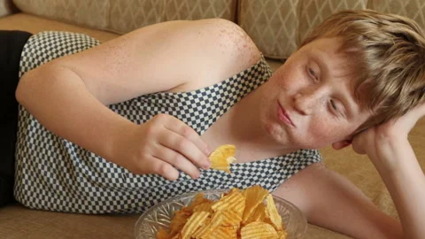Redhead boy eats chips on a sofa Stock Footage 204160857