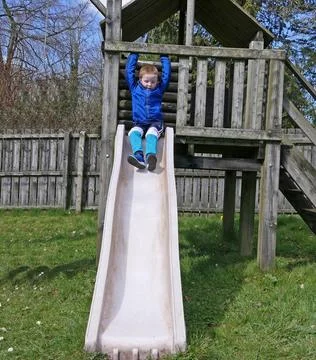 Redhead boy having fun playing on slides and swings at Playpark on a sunny da Stock Photos
