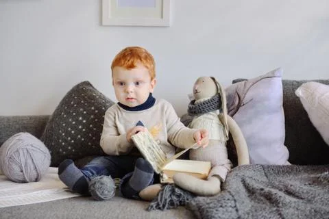 Redhead boy reading a book in front of Christmas tree Stock Photos