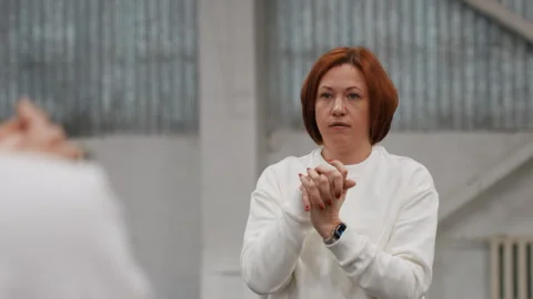 Redhead caucasian coach delivers feedback to player in indoor badminton court Stock Footage 341767407