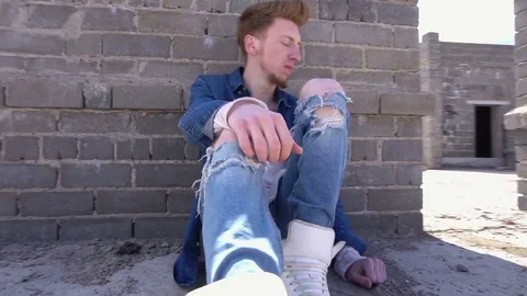 Redhead fashionable young man sitting on the floor of a roof in denim clothes Stock Footage