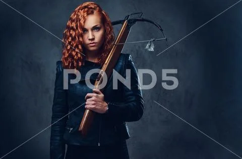 Redhead female holds crossbow. Stock Photos