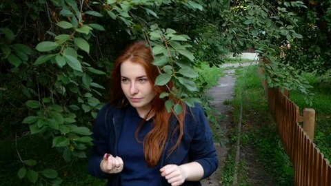 Redhead girl picks and eats cherry on the go Stock Footage 113402079