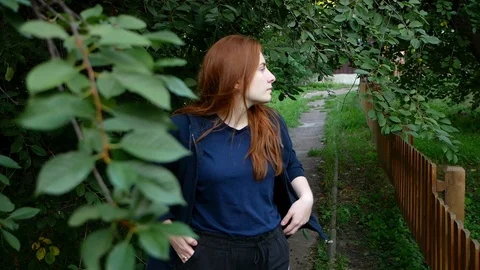 Redhead girl picks and eats cherry on the go Stock Footage 113404166