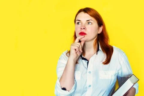 Redhead girl in white blouse  with books on yellow background. Copy space for Stock Photos