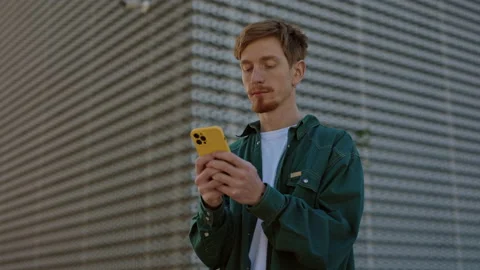 Redhead guy with piercing using smartphone on city street Stock Footage 162820688