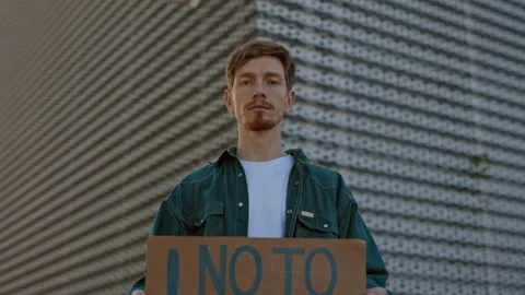 Redhead guy posing outdoors with no to racism banner Stock Footage 162658337