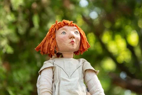 Redhead handmade puppet looking up with blurred trees in background 库存照片