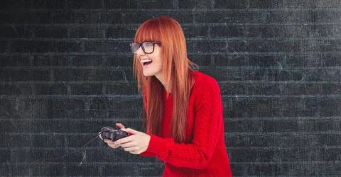 Redhead hipster playing video game against wall Stock Photos